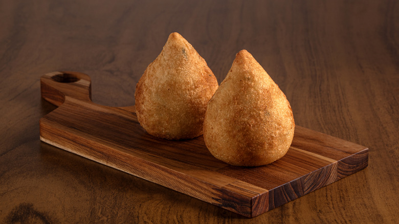 two coxinhas on wooden board