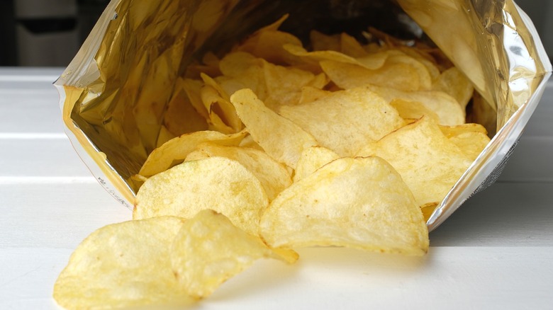 An open bag of potato chips, its contents spilling forth.