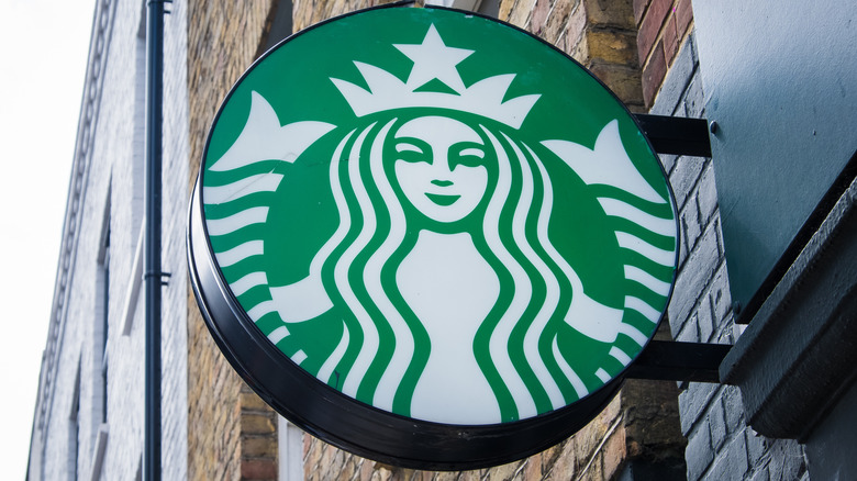 A Starbucks Logo sign hanging on the side of a building