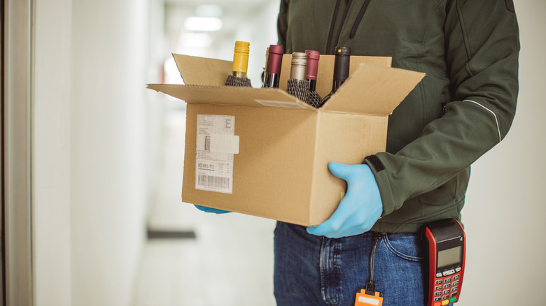 a deliveryman holding a box of bottles