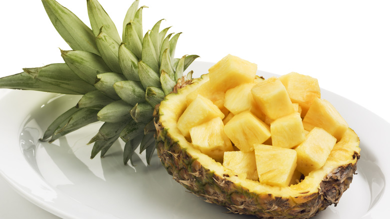 pineapple chunks in a pineapple boat on a white plate