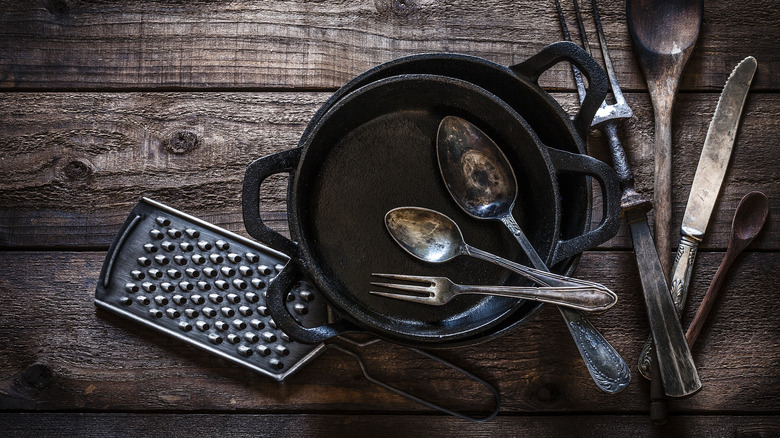 Rusty utensils in a cast iron skillet on a wooden surface