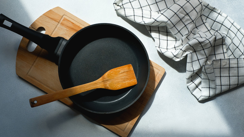 A cast iron skillet with a wooden spatula on a wooden cutting board.