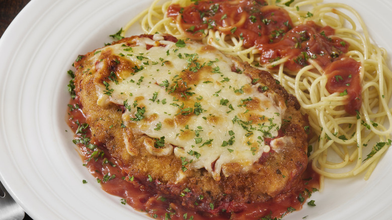 Chicken parmesan on a plate with spaghetti on the side