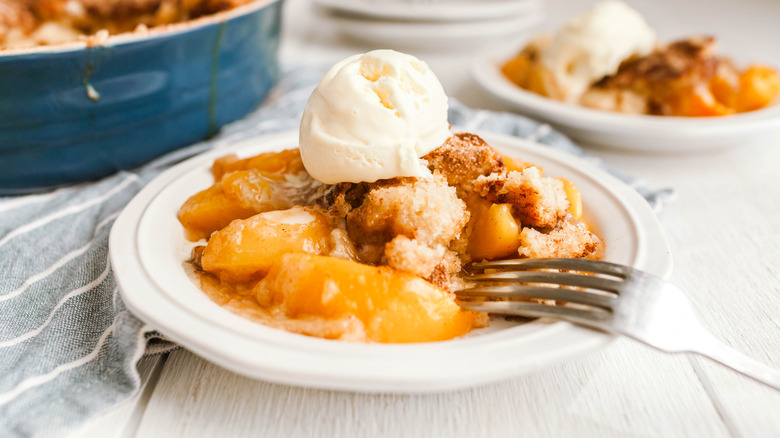 A small dish with peqach cobbler with a pastry topping that resembles cinnamon rolls