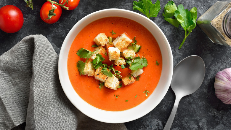 A bowl of tomato soup with garnish and croutons