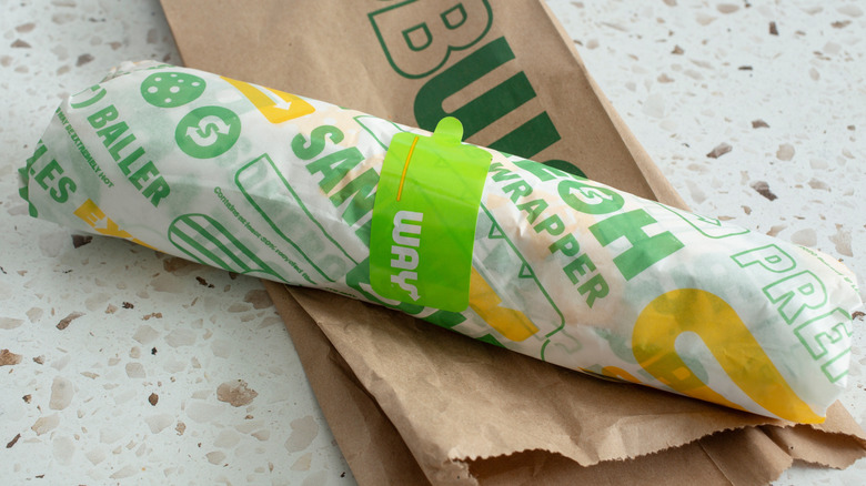 The wrapped subway sandwich and to-go bag on a table