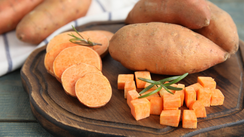 Whole, sliced, and cubed sweet potatoes on a wooden board