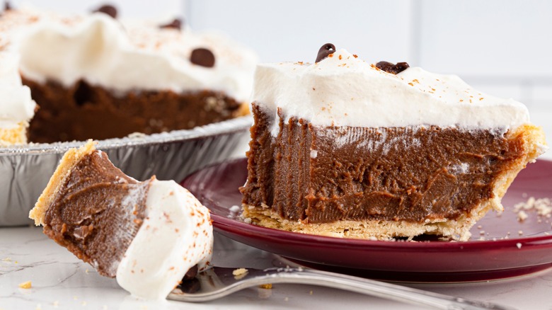 A slice of chocolate cream pie topped with whipped cream