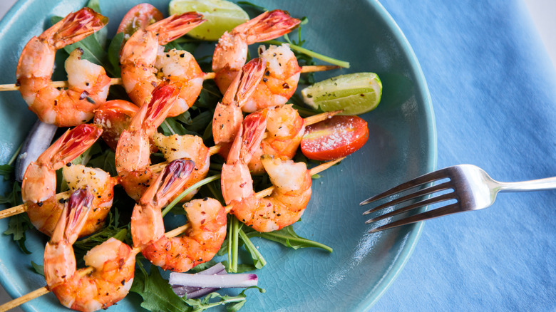 grilled shrimp on wooden skewers blue plate