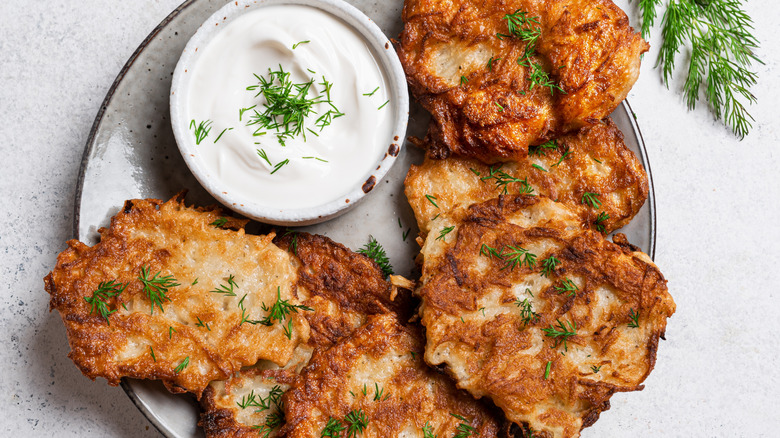 Latkes on a plate with sour cream as a dip.