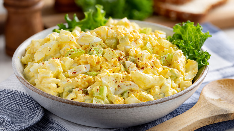 A bowl of egg salad sprinkled with paprika and garnished with lettuce