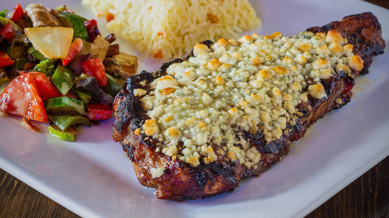 Cooked steak topped with a broiled blue cheese crust served with vegetables