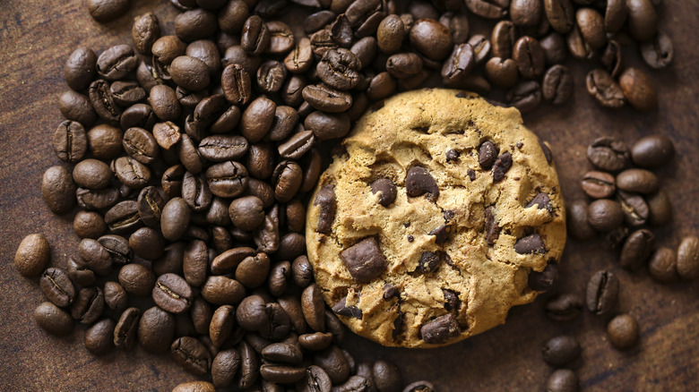 A chocolate chip cookie surrounded by coffee beans