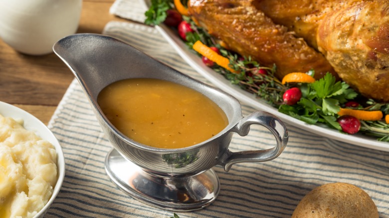 A gravy boat full of gravy on a striped cloth