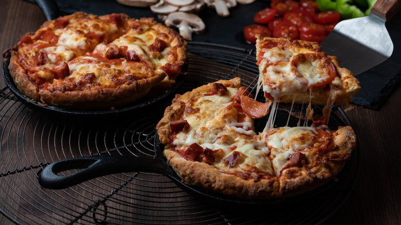 Two cooked pizzas in cast iron pans