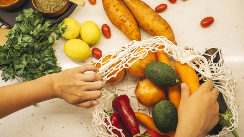 a macramé bag with produce being emptied by hand