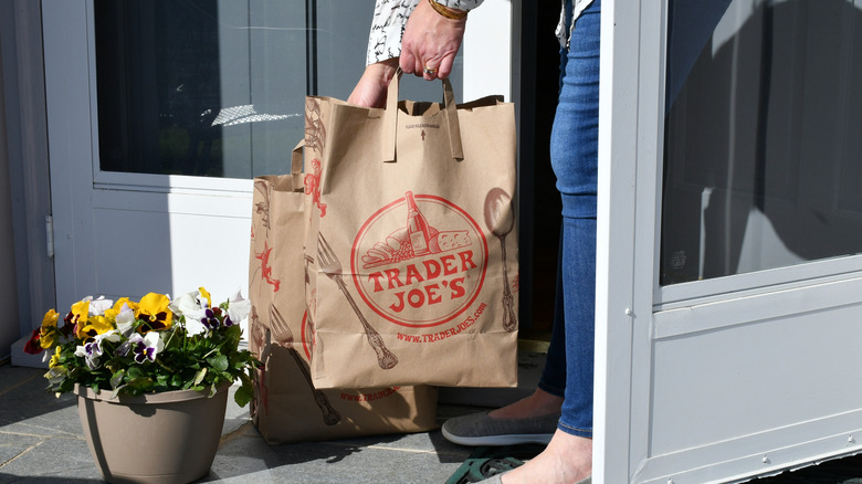 woman picking up bags of Trader Joe's groceries