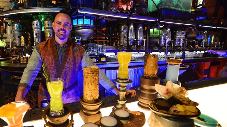 A bartender at Oga's Cantina poses at the bar with a selection of drinks