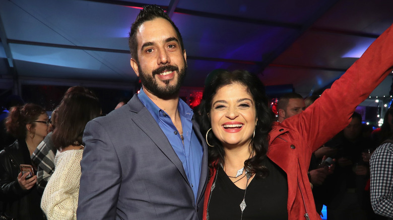 Alex Guarnaschelli thrusts one arm up while hugging Michael Castellon