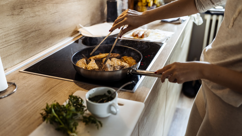 woman frying fish in skillet on stove