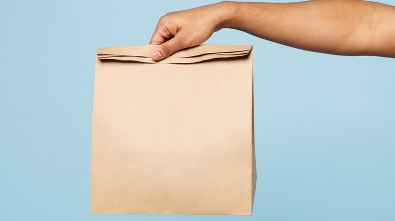 arm holding brown paper bag