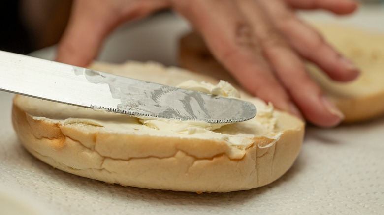 Hand spreading cream cheese on bagel