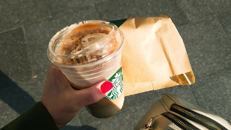 Hand holding a cup of Starbucks iced coffee.