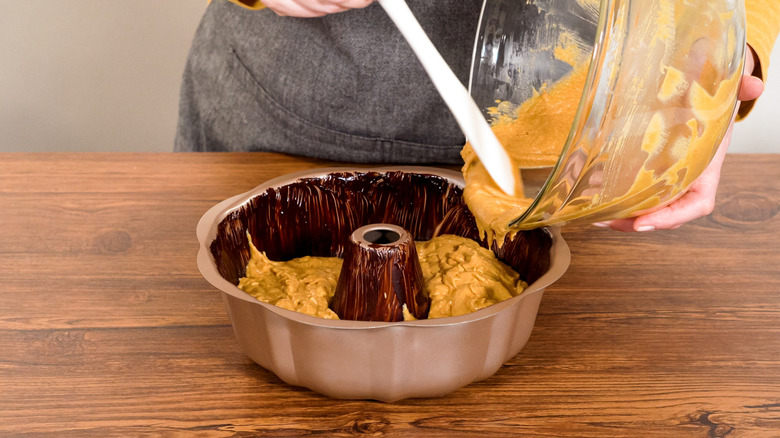 Baker filling a bundt cake pan with batter