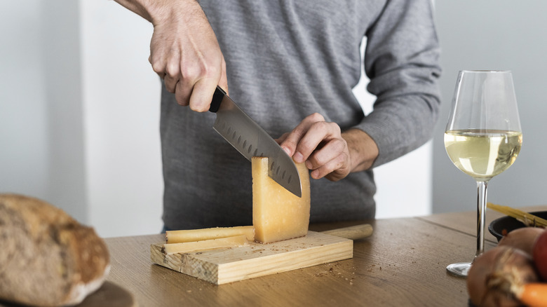 man cutting hard cheese