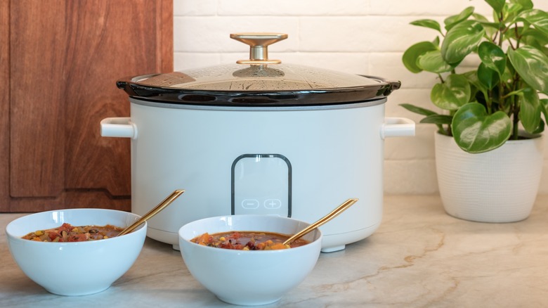 Slow cooker with two bowls of stew in front of it