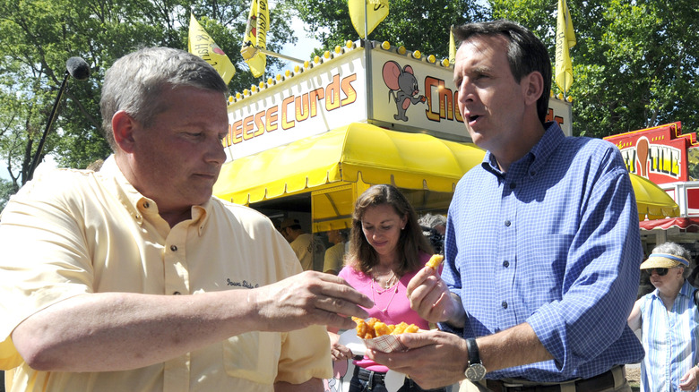 Two men sharing a dish of fried cheese curds in front of a cheese curd food truck