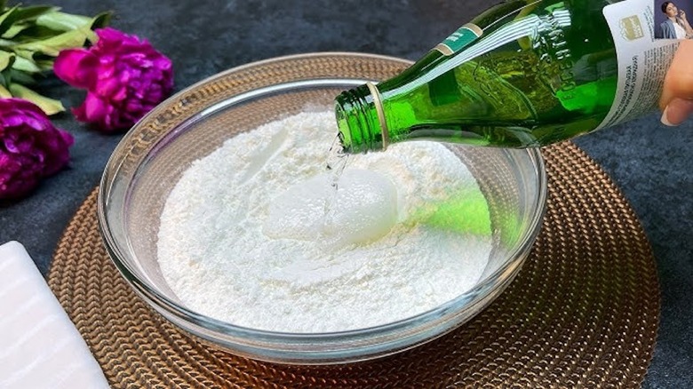 Person pouring carbonated water into a bowl of baking mixture