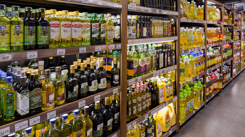 A grocery store aisle stocked with bottles of olive and canola oil