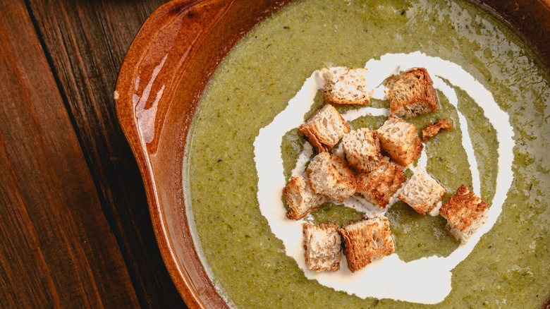 Creamy broccoli soup with a swirl of cream and croutons on top