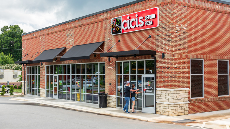 Two people entering a Cicis Pizza restaurant