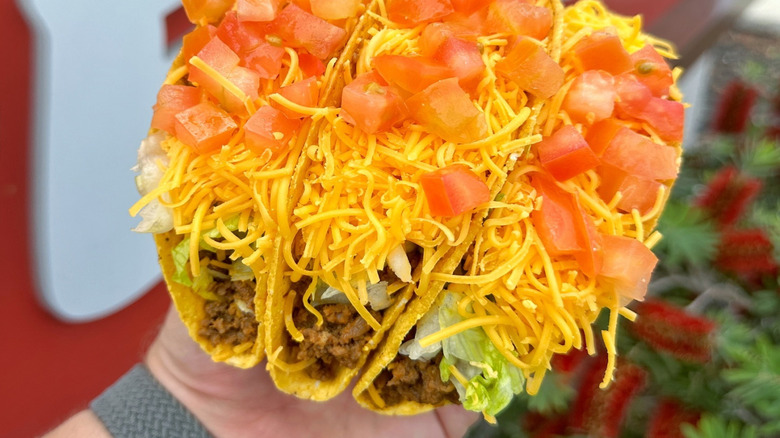 Three loaded cripsy tacos stuffed with cheese, ground beef, and tomatoes