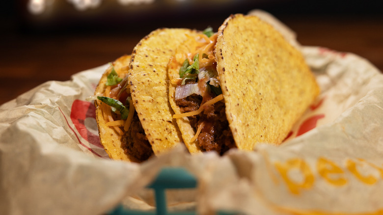 Crispy tacos stuffed with ground beef, cheese, and cilantro on a paper plate