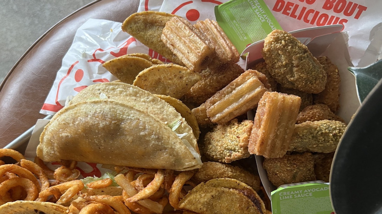 A plate filled with crispy tacos, churro sticks, curly fries, and nuggets