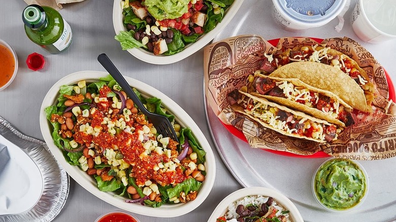 Table with bowls of guacamole, salad, and tacos