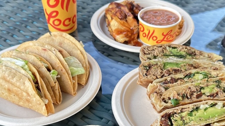 Plates on a table with tacos, burritos, and chicken with beans