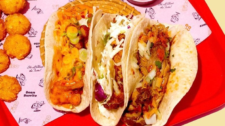 Three tacos on a red tray