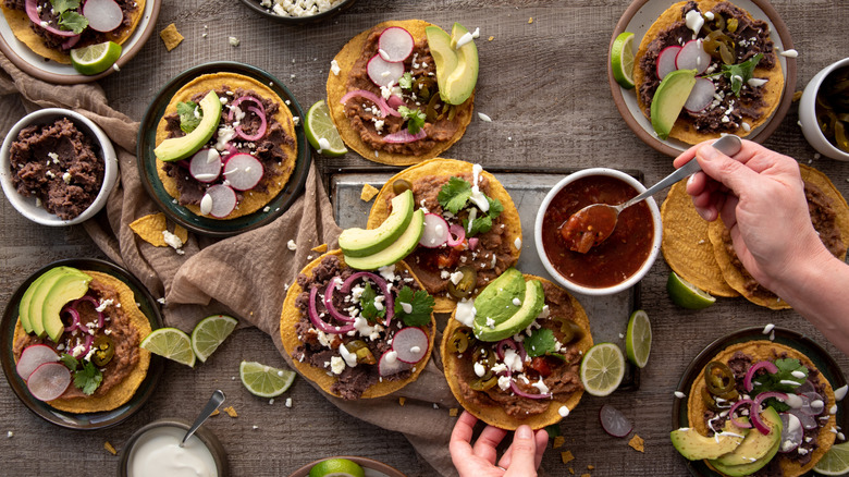 A table full of tacos with shredded meat and avocado