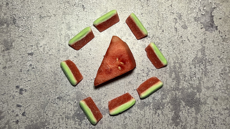 Watermelon gummies surround an actual piece of watermelon