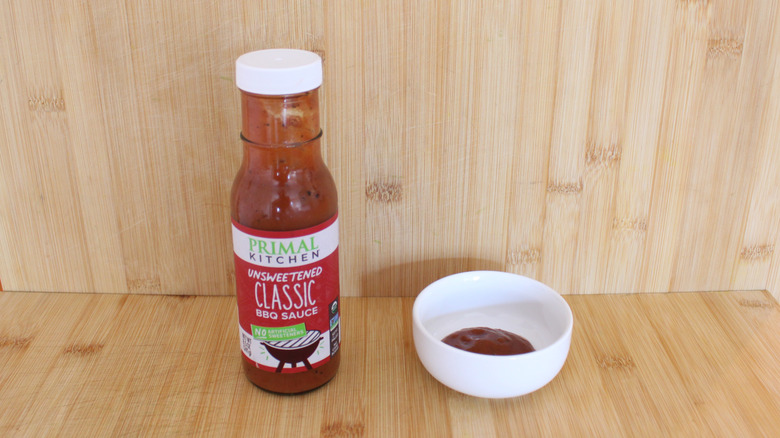 Container and bowl of Primal Kitchen Unsweetened Classic BBQ Sauce