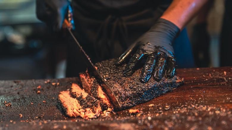 Gloved hands slicing a barbecue brisket