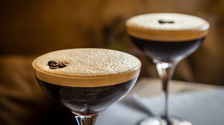 two espresso martinis with foamy heads and the traditional three espresso bean garnish