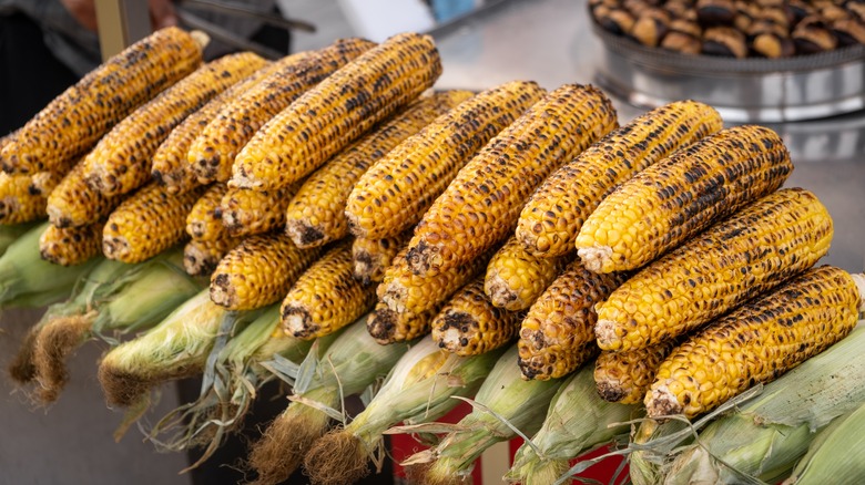 A stack of grilled ears of corn for sale at a market.