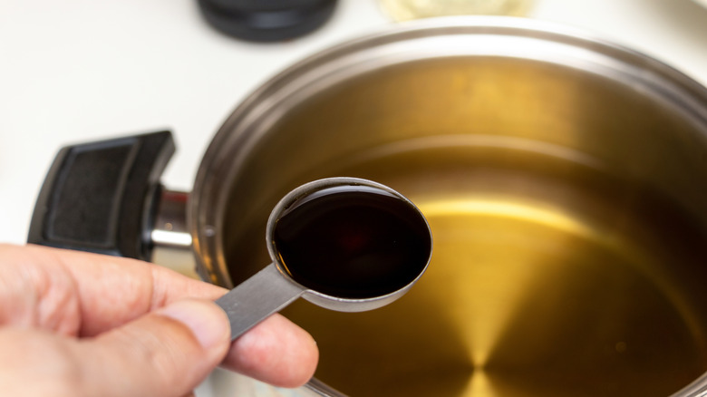 Person adding soy sauce to a pan