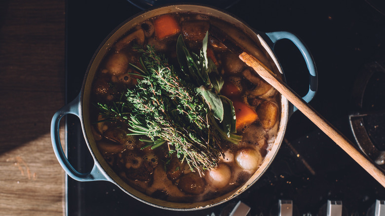 A beef stew with herbs and vegetables on a stove